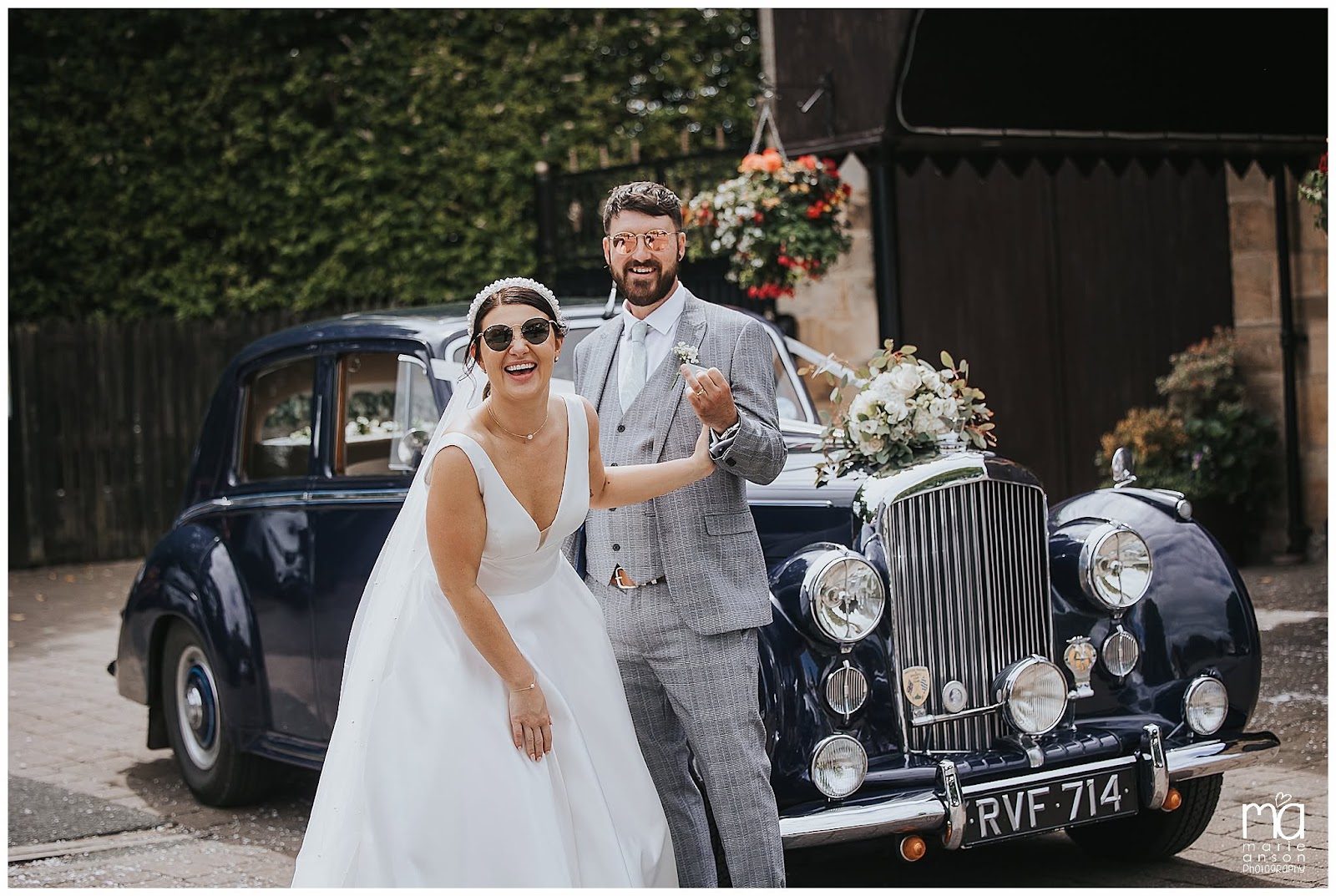 A couple beside their vintage wedding car outside The Engine Shed
